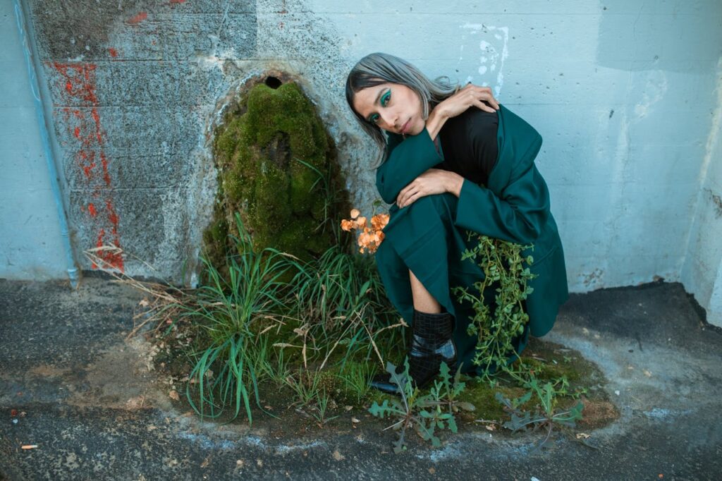 Person in Black Jacket and Blue Denim Jeans Sitting on Rock